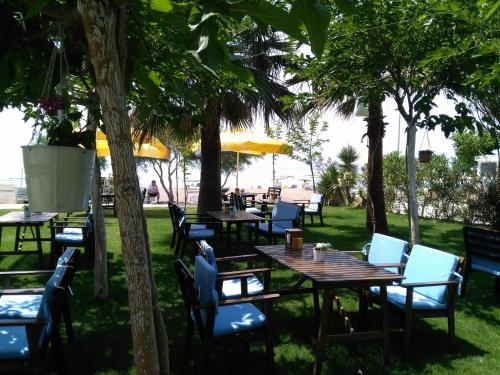 un restaurante al aire libre con mesas y sillas bajo los árboles en Palmiye Hotel, en Özdere