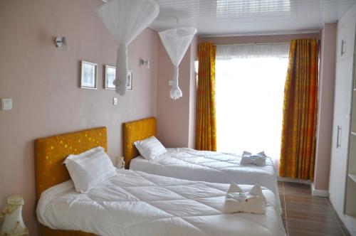 1 dormitorio con 2 camas y ventana en Lamanis Haven, en Kakamega