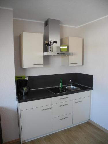 a kitchen with white cabinets and a sink at Appartements Fischerhus in Glowe
