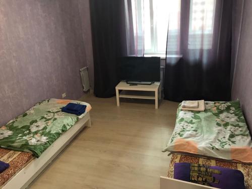 トヴェリにあるApartments Pskovskayaのベッド2台、テレビ、テーブルが備わる客室です。