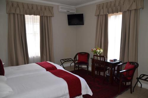 a hotel room with a bed and a table and chairs at Lemoenkloof Boutique Hotel in Paarl