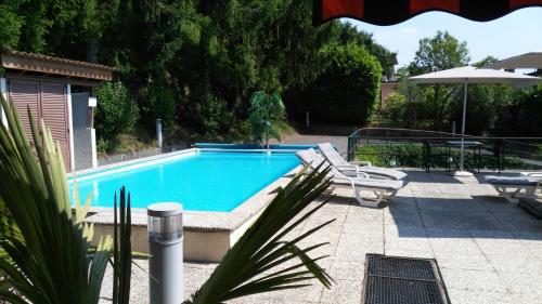 a swimming pool with two chairs and an umbrella at Hotel Morgana in Mendrisio