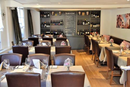 un restaurante con mesas, sillas y botellas de vino en JUCKERs Boutique-Hotel, en Tägerwilen