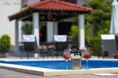 twee glazen wijn naast een zwembad bij Apartment Mihanovic only for family with children in Žrnovnica
