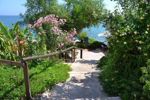 a path leading to a garden with flowers and the ocean at Aphrodite Beach Hotel in Polis Chrysochous
