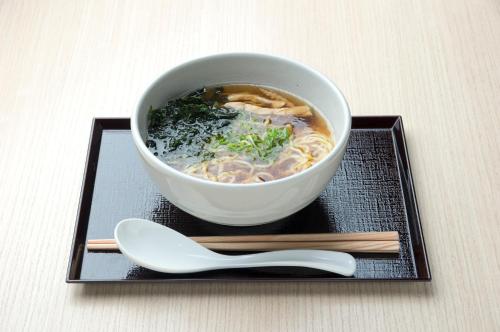 a bowl of soup on a plate with chopsticks at Dormy Inn EXPRESS Sendai Seaside in Sendai