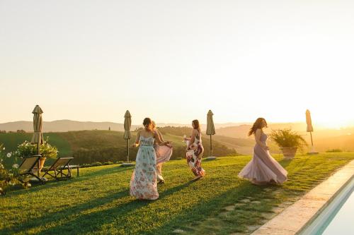a group of women walking on the grass by a pool at Podere Cunina in Buonconvento
