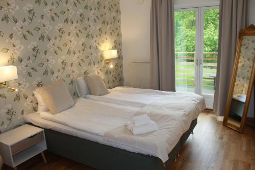 a bedroom with a bed with white sheets and a mirror at Hensbacka Herrgård in Munkedal