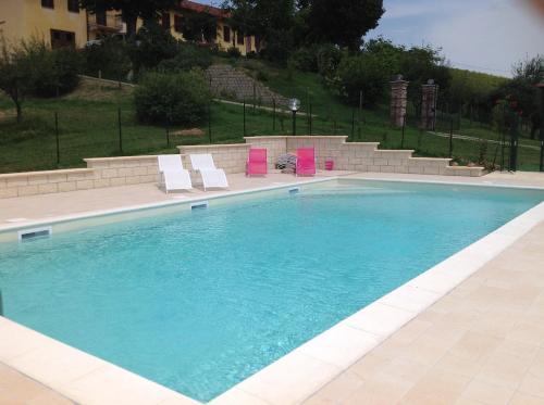 a large swimming pool with two chairs at Agriturismo Tre Tigli in Asti