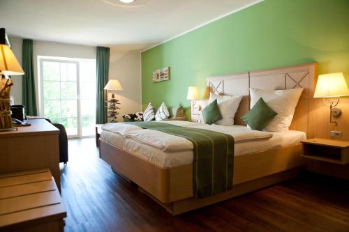 a bedroom with a large bed with green walls at Kathmeyers Landhaus Godewind in Sankt Peter-Ording