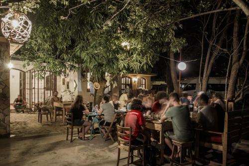 a group of people sitting at tables in a restaurant at night at Caracolito Hostal in Las Peñitas