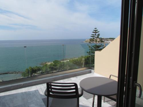 a table and chairs on a balcony with a view of the ocean at Archipelagos Hotel in Rethymno Town