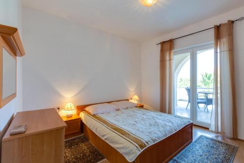 a bedroom with a bed and a window with a table at Apartmani GORDANA in Mali Lošinj