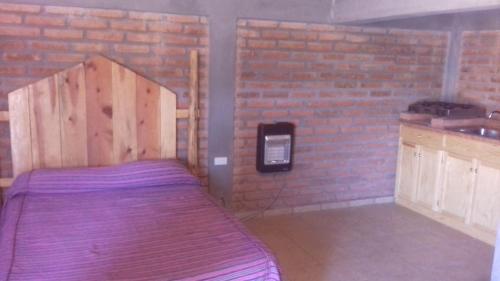 a bed in a room with a brick wall at Cabañas Margarito in Areponapuchi