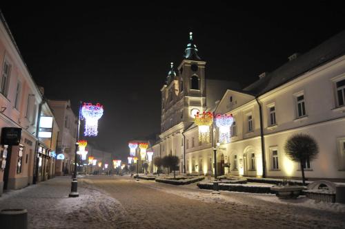 Una calle nevada por la noche con una iglesia con luces navideñas. en Hostel Promenada, en Rzeszów