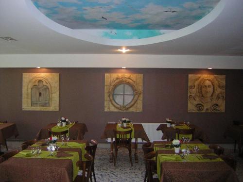 a dining room with green tables and chairs and a ceiling at Hôtel Bertrand in Bar-le-Duc