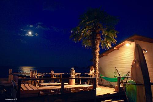 a woman sitting on a deck next to a palm tree at PavilionSurf&Lodge in Shishikui