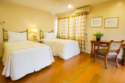 a bedroom with two beds and a table and a chair at Sophia Suites Residence Hotel in Cebu City