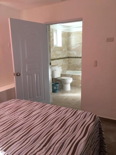 Un dormitorio con una cama y un baño con inodoro. en Casita Blanca Bayahibe, en Bayahibe