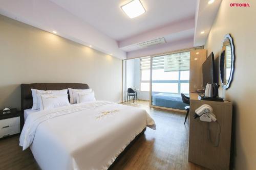 a bedroom with a large white bed and a television at Hotel Lohas in Boryeong