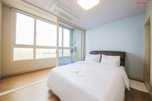 a white bed in a room with a large window at Hotel Lohas in Boryeong