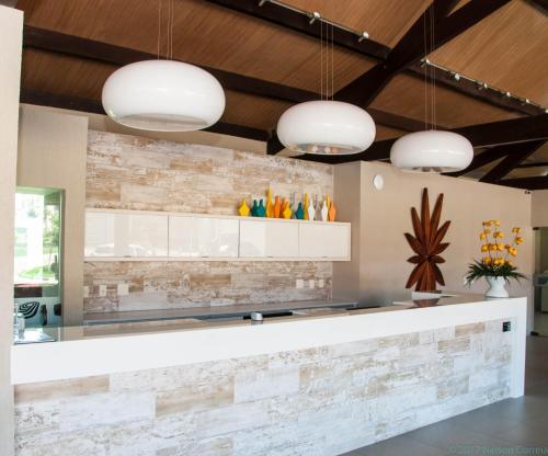a kitchen with a stone wall and three pendant lights at Apto Oka Beach Residence in Porto De Galinhas