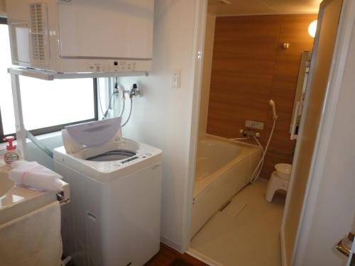 a bathroom with a toilet and a sink and a tub at MihaMac in Chatan