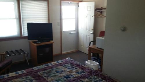 a bedroom with a bed and a flat screen tv at Skyline Motel in Alexandria