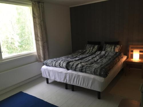 a bedroom with a bed with a window and a lamp at Gran Hotellihuoneistot 2 in Suolahti