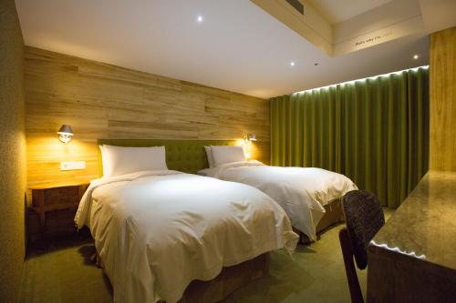 a bedroom with two beds and a green curtain at Inhouse Hotel Taichung in Taichung