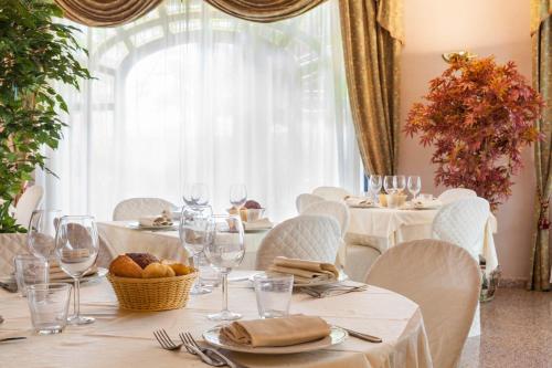 a dining room with white tables and chairs and a window at Hotel Le Rotonde in Massaciuccoli