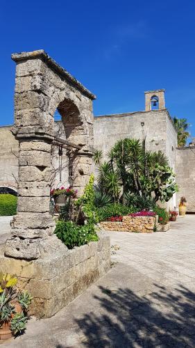 a stone building with a flower garden in front of it at Relais Masseria Casina dei Cari in Presicce