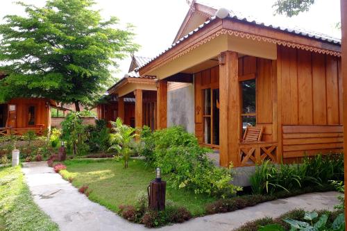 a wooden house with a garden in front of it at Baan Aew Pai in Pai