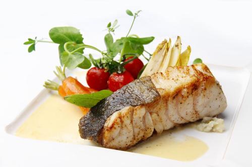 a plate of food with a piece of fish and vegetables at Charmehotel Manoir Ogygia in Poperinge