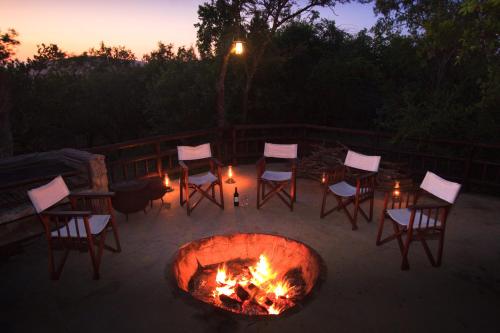 a fire pit with chairs and a table and afire at Shayamoya Tiger Fishing and Game Lodge in Pongola Game Reserve