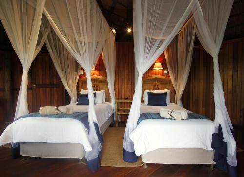 two beds in a room with drapes at Shayamoya Tiger Fishing and Game Lodge in Pongola Game Reserve