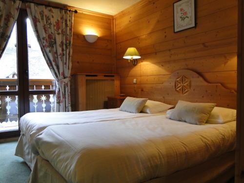 ein Schlafzimmer mit einem großen Bett in einem Zimmer mit Holzwänden in der Unterkunft Le Caprice Des Neiges in Crest-Voland