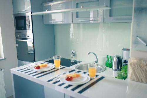 a kitchen with two plates of fruit and two glasses of orange juice at Apartament Zeus in Zielona Góra