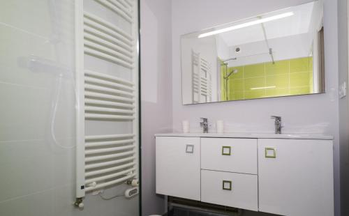 une salle de bain blanche avec un lavabo et un miroir dans l'établissement Le Courtoisville Apartment, à Saint-Malo