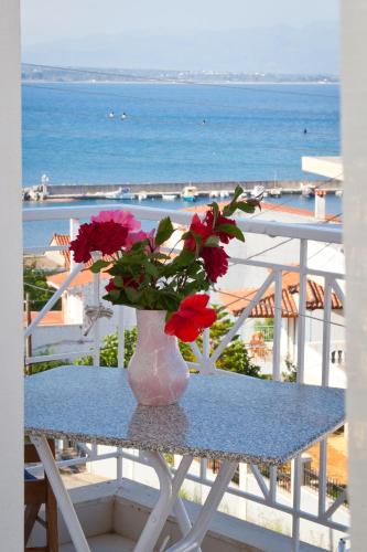 a vase with flowers sitting on a table with the ocean at Erato Apartments in Petalidhion