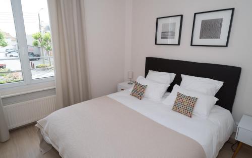une chambre avec un lit blanc avec des oreillers et une fenêtre dans l'établissement Le Courtoisville Apartment, à Saint-Malo