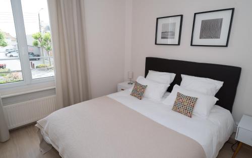 a bedroom with a white bed with pillows and a window at Le Courtoisville Apartment in Saint Malo