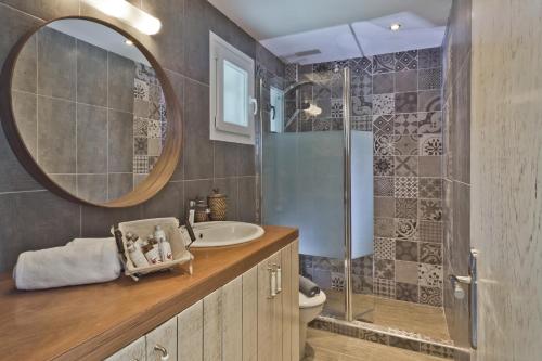 ein Bad mit einem Waschbecken und einer Dusche mit einem Spiegel in der Unterkunft Antikri villas in Kyra Panagia