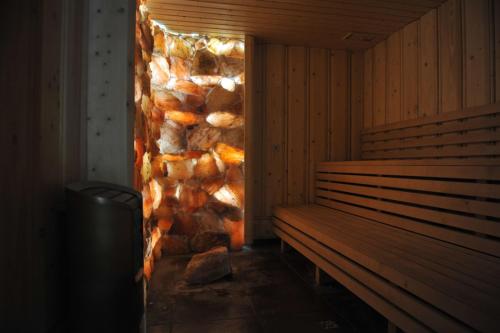 a sauna with a stone wall and a wooden bench at Hotel Chutor Kozacki in Łukowe