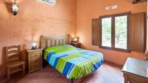Un dormitorio con una cama y un escritorio y una ventana. en Complejo Rural El Molinillo, en Arenas del Rey