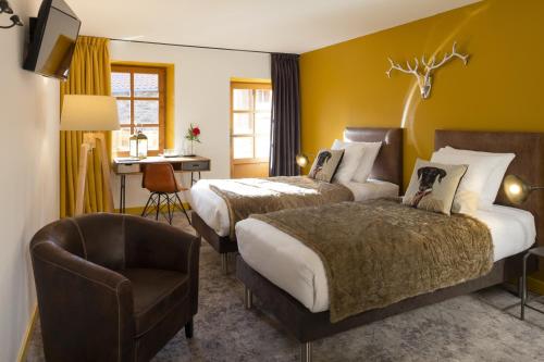 a hotel room with two beds and a chair at Contact Hôtels Le Savigny & Spa in Blacé