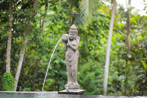 a statue of a child with a fountain at Ayu Duwur Beji in Ubud