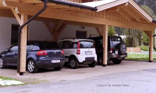 a garage with two cars parked under a wooden structure at Ahrnerhof in Leutasch