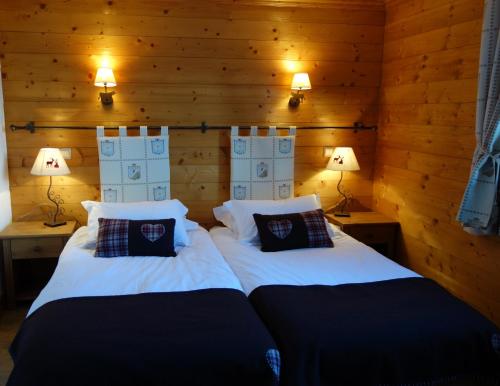two beds in a room with wooden walls and lights at Appart 4 pers proximité lac et remontées Le Praz - Arrayanes in Courchevel