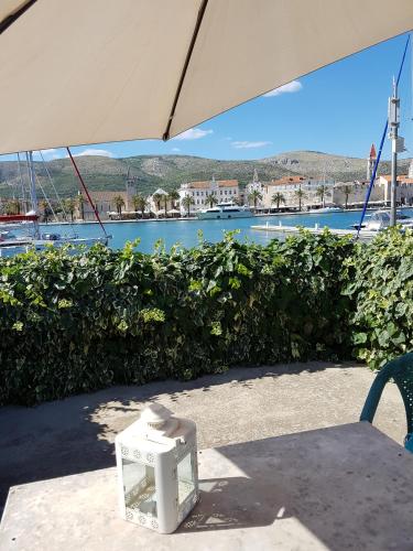 a table with an umbrella in front of a body of water at Room Cvita in Trogir